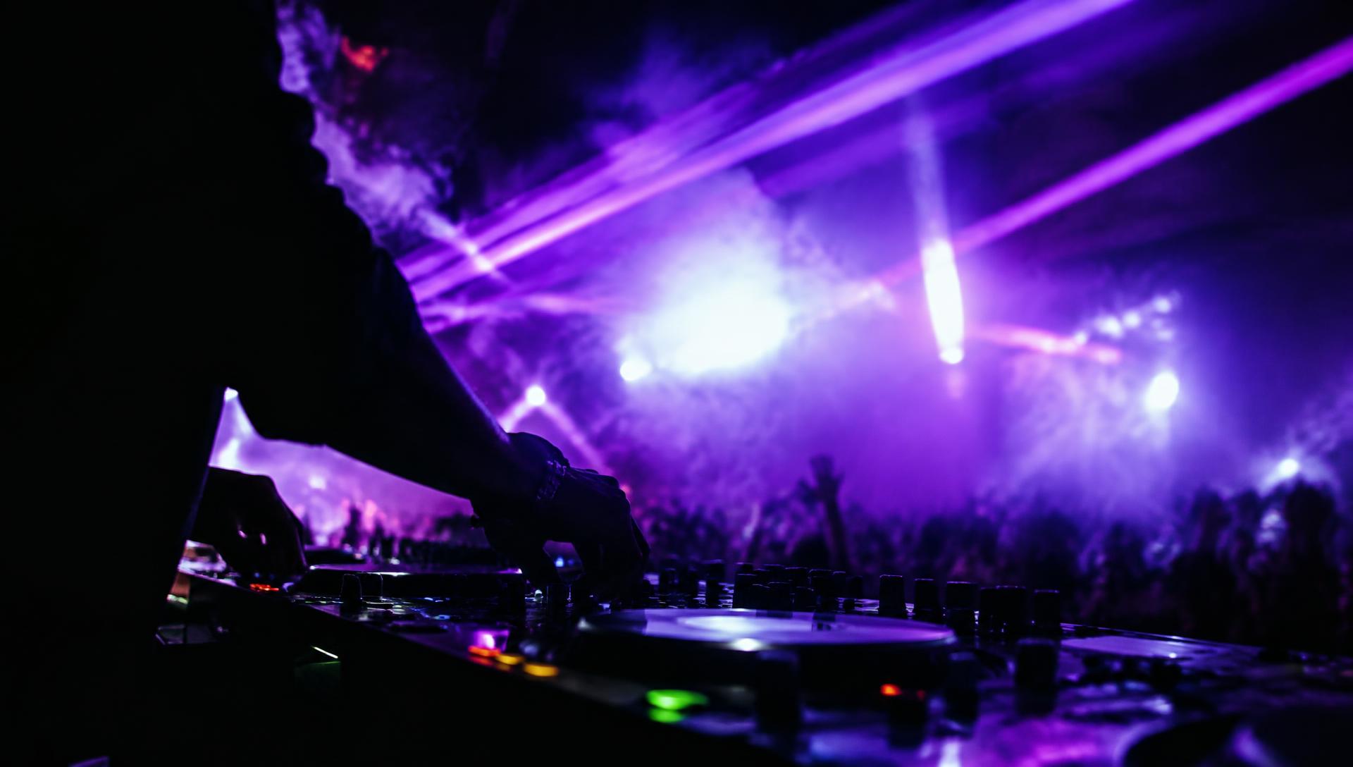 DJ tocando com luzes e fumaça sobre o público